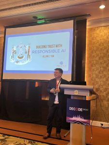 Allan Tan standing at a lectern presenting a slide titled 'Building Trust with Responsible AI' at the DECODE 2024 conference